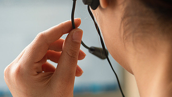 Frau mit Headset vor einem verschwommenen Computerbildschirm