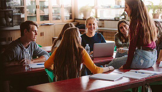 Schülerinnen und Schüler unterhalten sich während einer Unterrichtspause im Klassenzimmer.