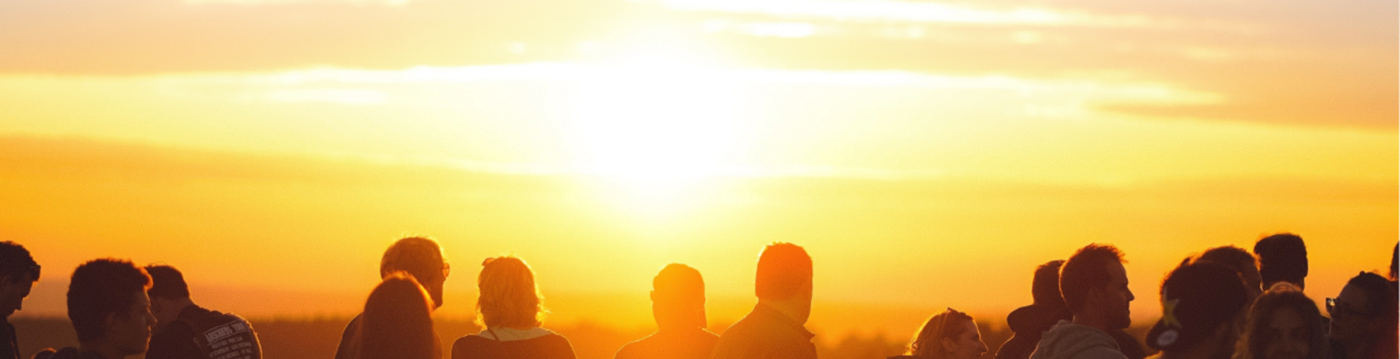 Eine Gruppe von Menschen schaut sich den Sonnenuntergang an.